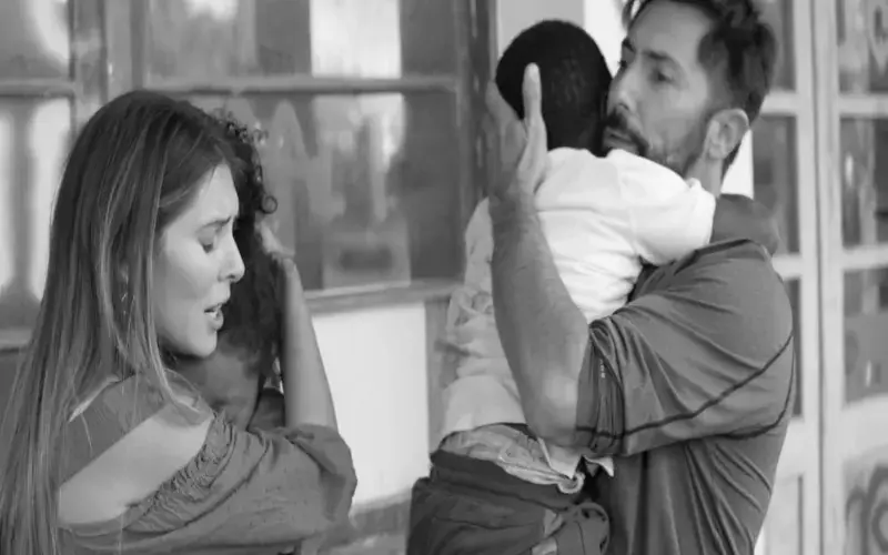 Man hugging a child, woman looking with concern.